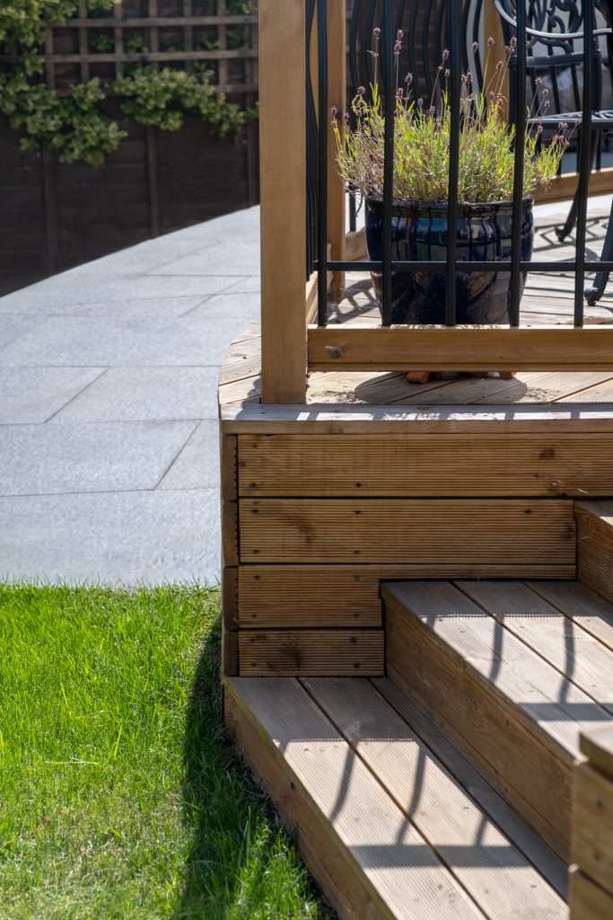 A sunny garden with a tiled slope and deck steps.
