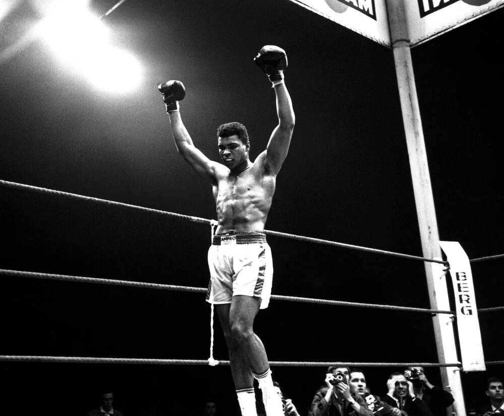 Monochrome picture of Muhammed Ali rasing his hands in victory.